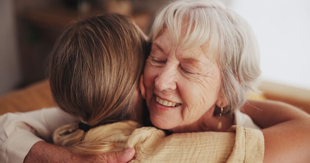 an older person and their daughter hugging after talking about asking for help.