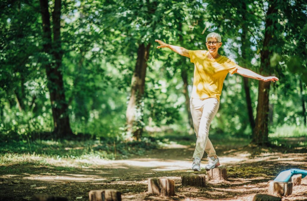 A senior walks along a balance obstacle, wearing a smile.