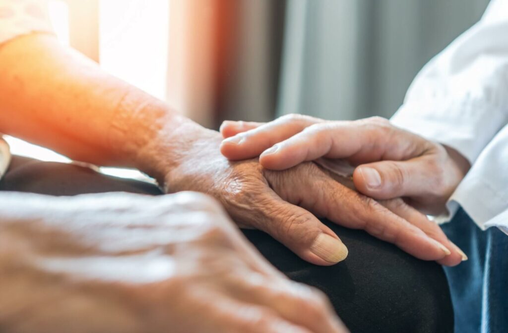 Close-up of one person gently placing their hand over another’s in a caring gesture