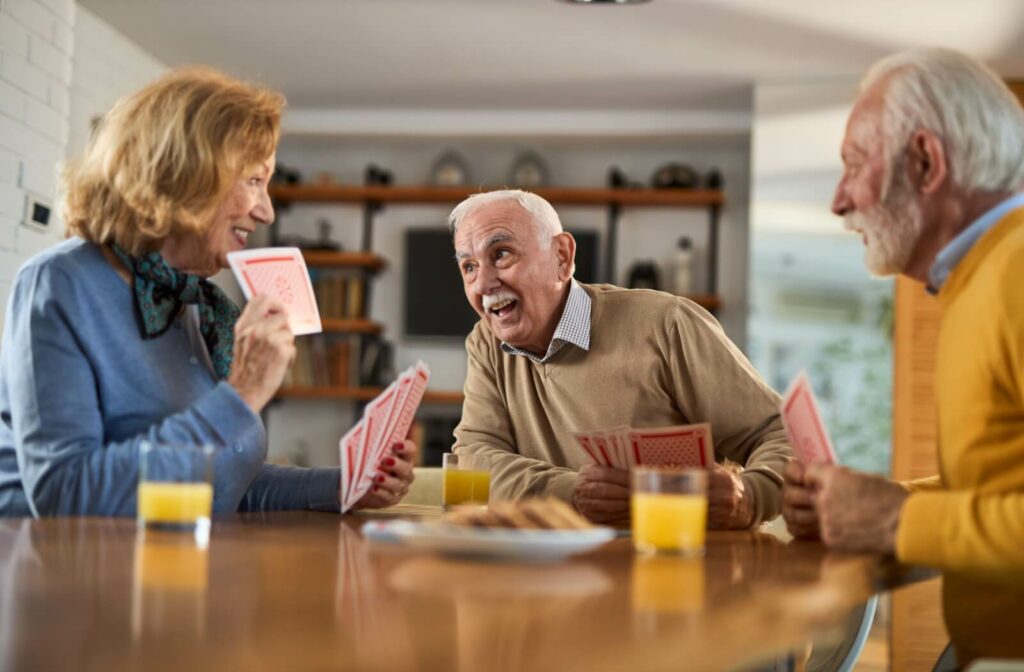 A group of happy seniors are having fun while playing cards in an assisted living community.