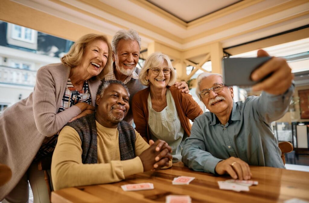 A group of seniors smile at a phone as they take a selfie together.